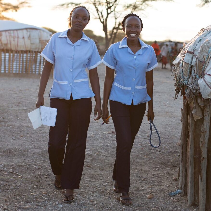 Two Kenyan female nurses walking through a rural village location. Kenya, Africa.