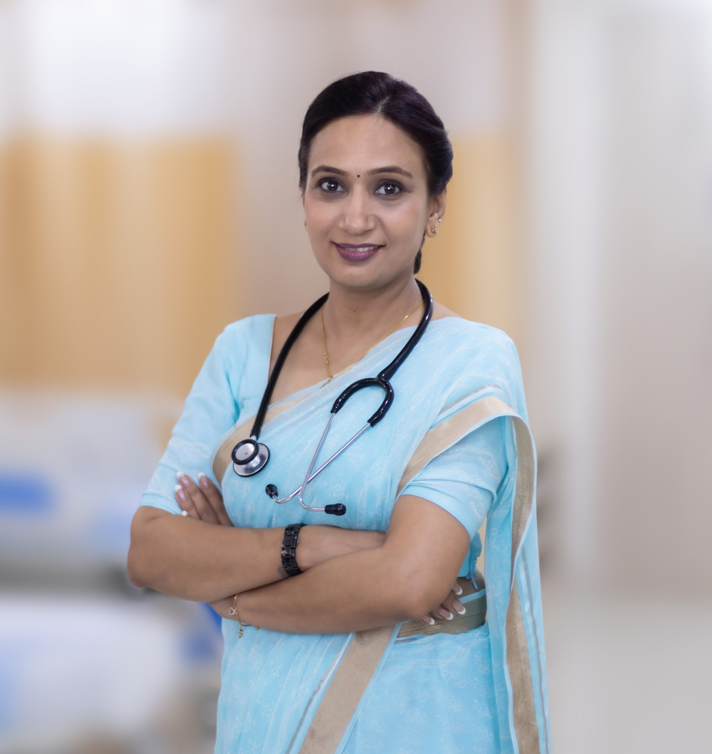 Smiling female Indian doctor in light blue sari with a stethoscope around her neck.
